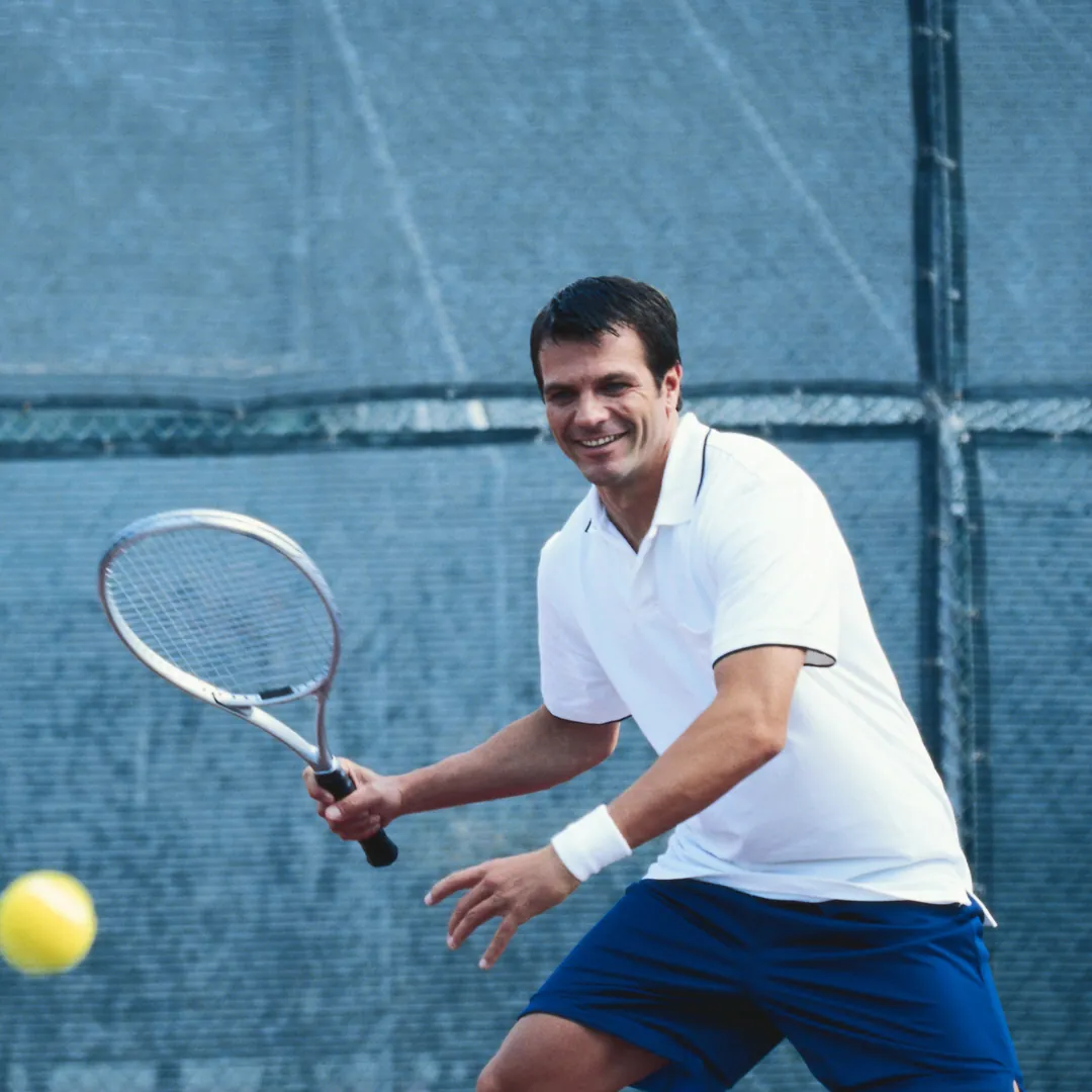 Adult man smiling as he runs for a forehand