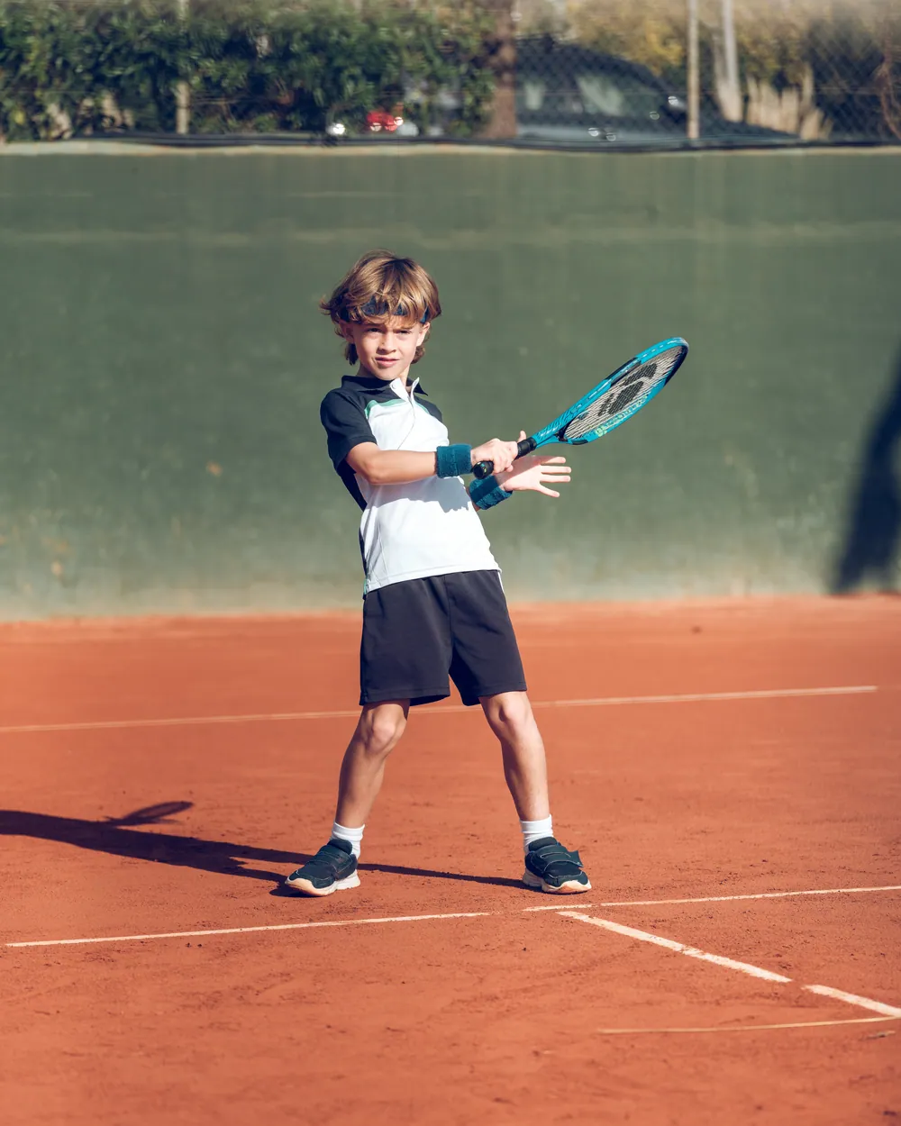 Junior boy hitting a forehand on a clay tennis court