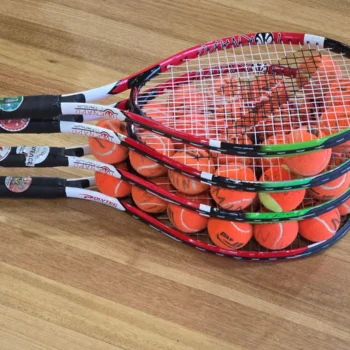 Junior tennis racquets stacked with orange training balls