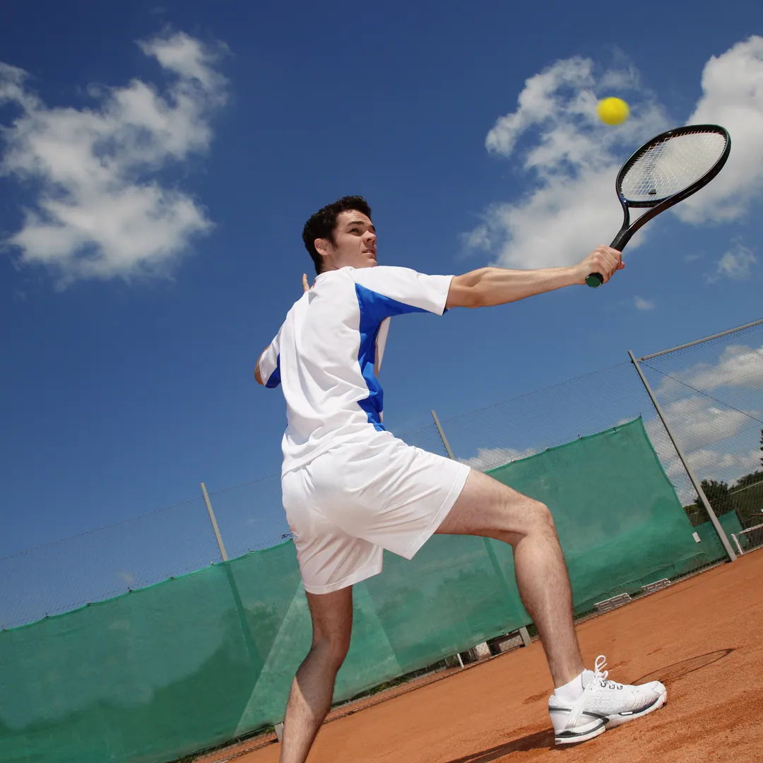 Player stretching to hit a ball under a cloudy sky