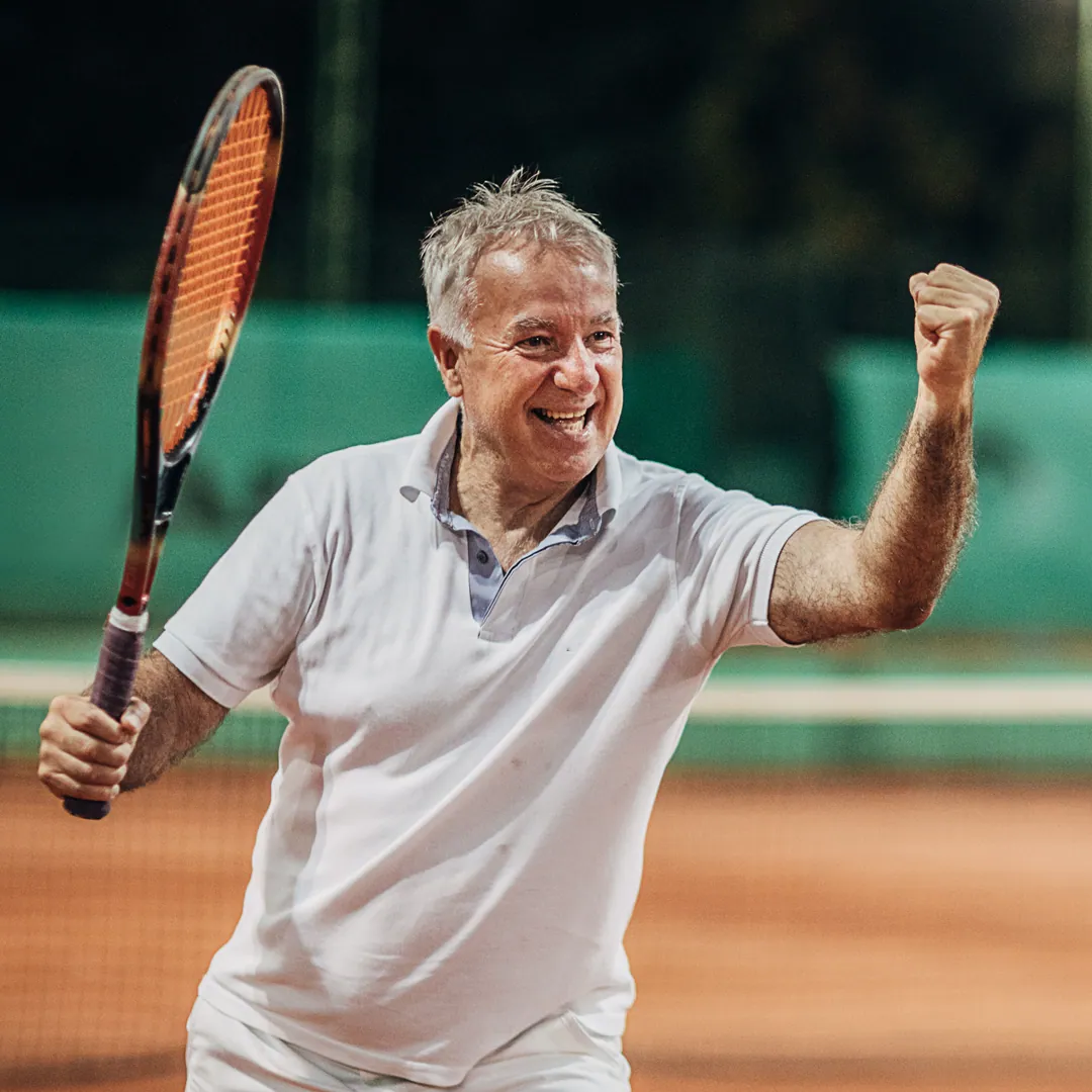Senior man celebrating a point on a clay court