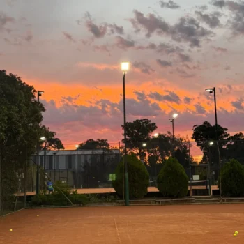 Sunset over a floodlit clay tennis court