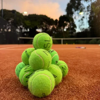 Tennis balls stacked in a pyramid on a clay court