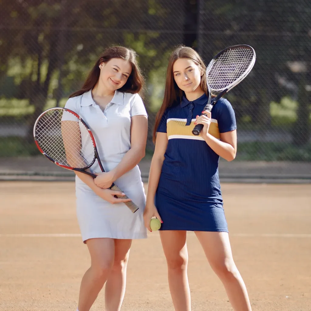 Two teenage girls standing on court with their racquets