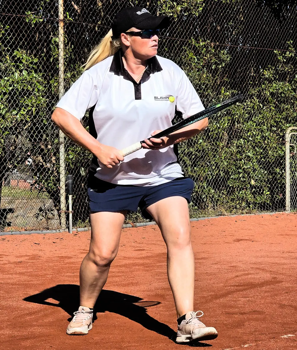 Vicky Lee, founder and head coach of Slamin Tennis, in the ready position on a clay court